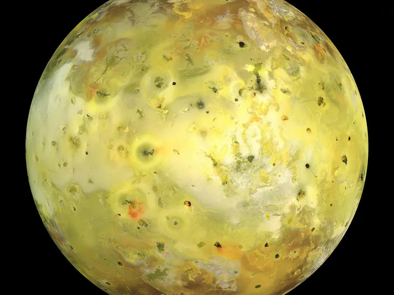 A yellow, orange and white moon, blotched with dark volcanic spots