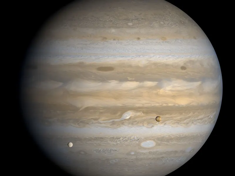 Jupiter’s striped clouds filling the frame, with two small moons, Io and Europa, in front of it
